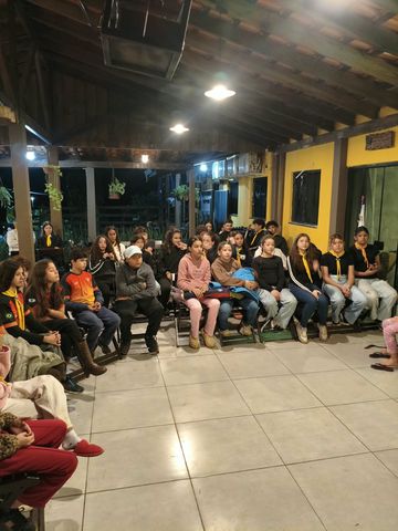 Participantes sentados em uma área coberta durante uma atividade do acampamento de instruções.